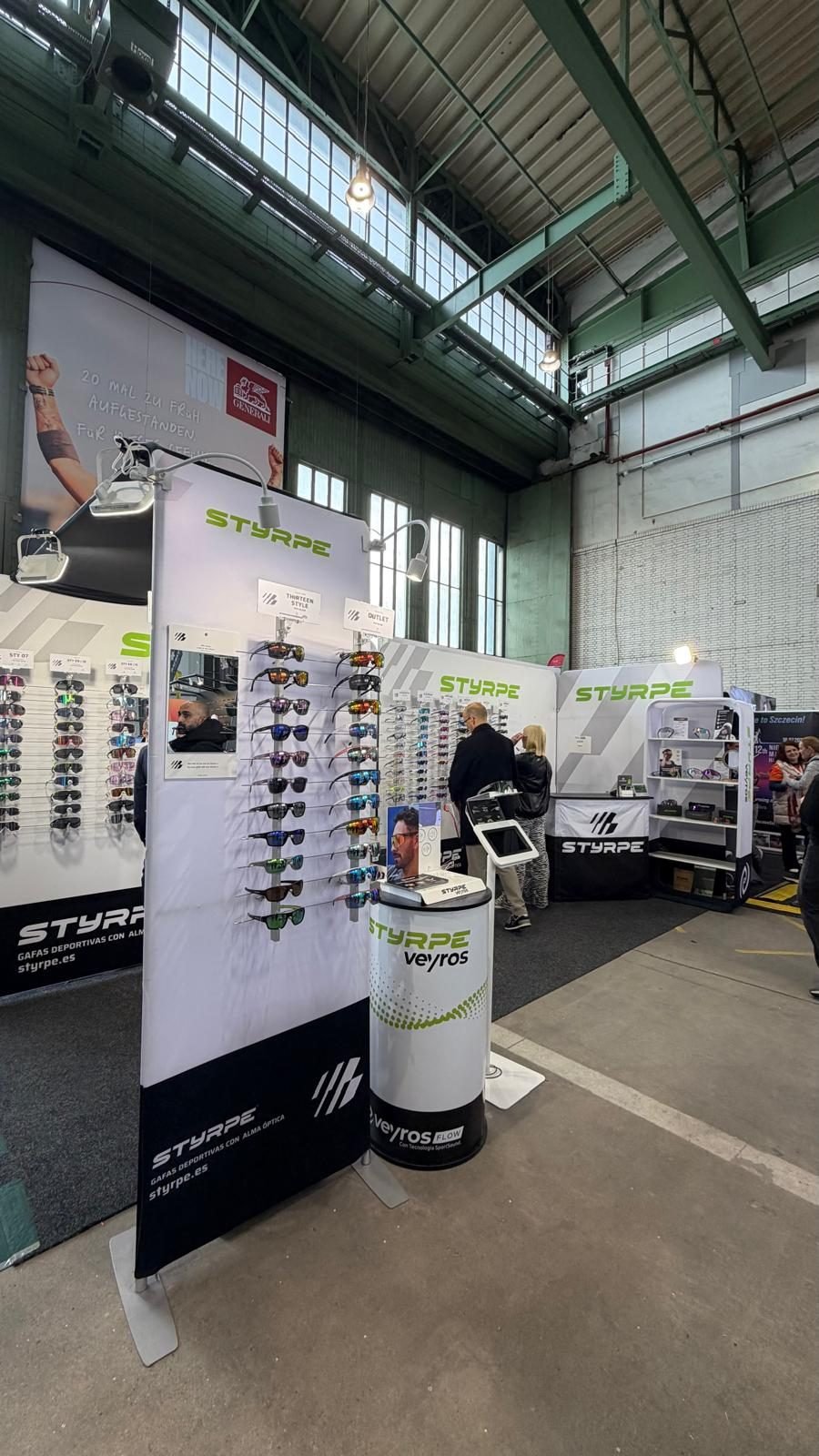 Stand de STYRPE en una feria, con expositores de gafas deportivas